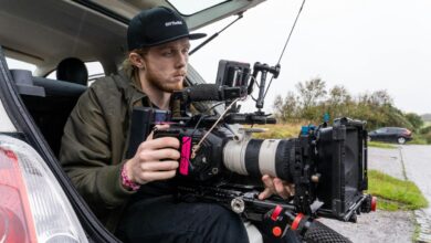 Cinegrafista com câmera de cinema profissional montada em rig, filmando em locação a partir do porta-malas do carro